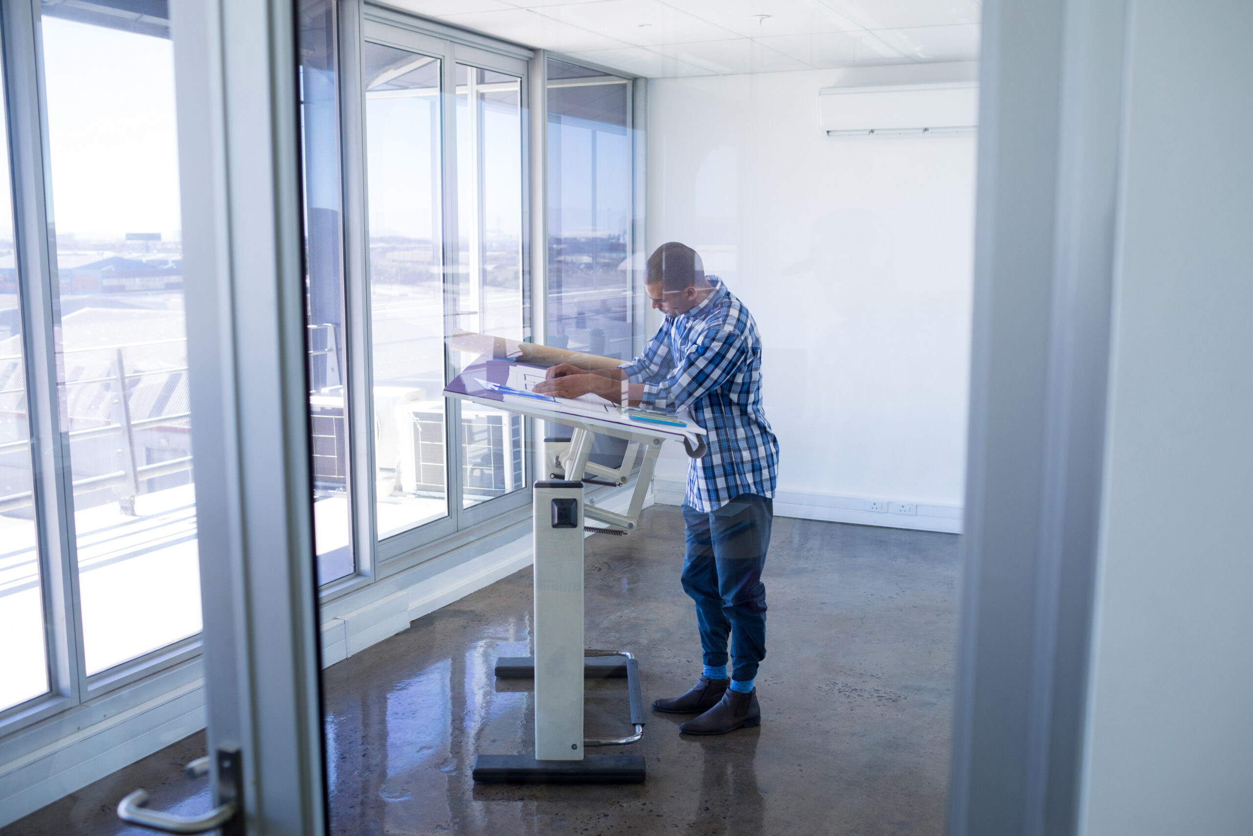 SYgnus office partnership technology solutions Male executive working over drafting table man near a window at a standing desk